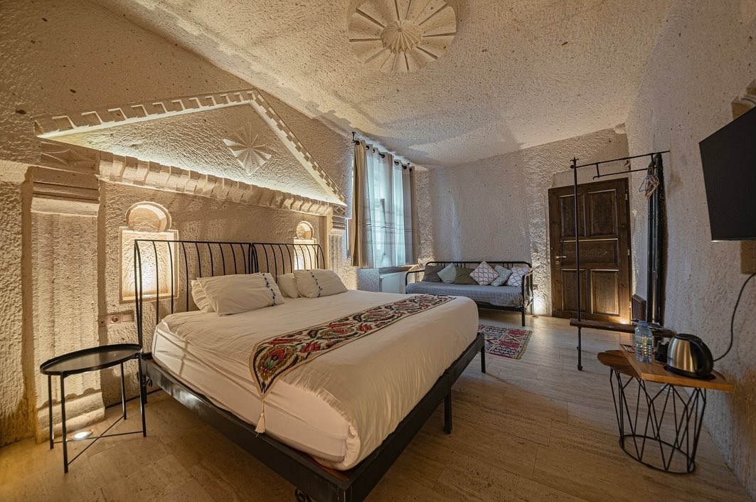 304 Deluxe Cave Room: alınlıklı oyma başlık, ferforje yatak ve oturma köşesi